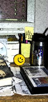 Messy desk with yellow happy face stress ball.